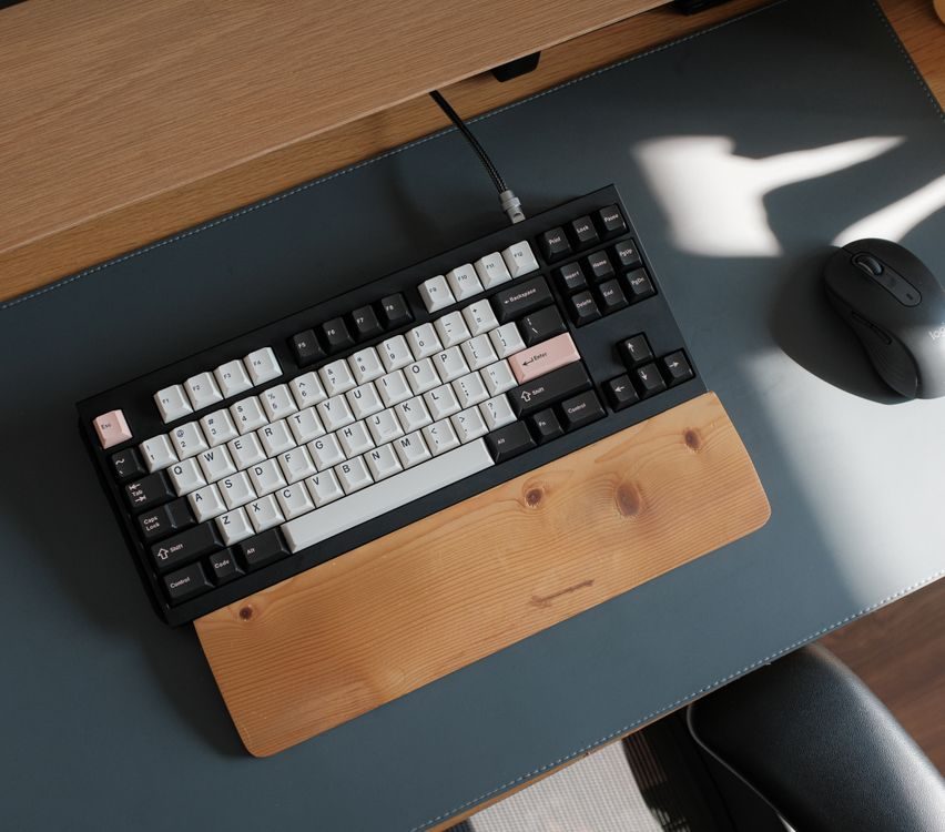 Mechanical keyboard with a wooden wrist rest and mouse on a desk